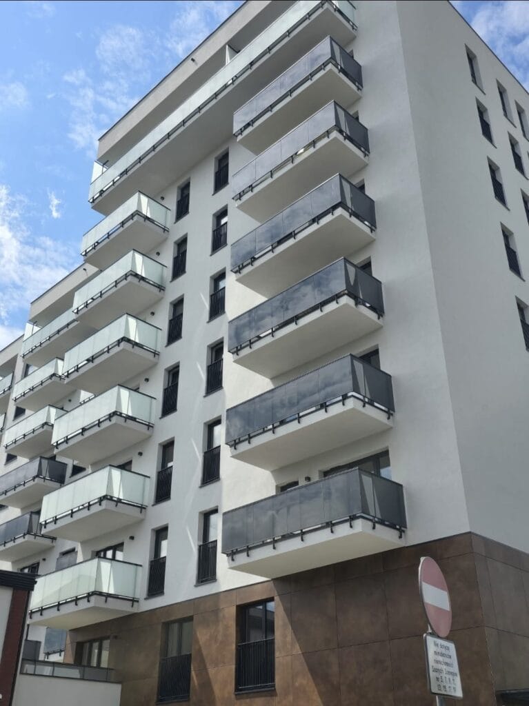 nowoczesny budynek wielorodzinny z balkonami szklanymi